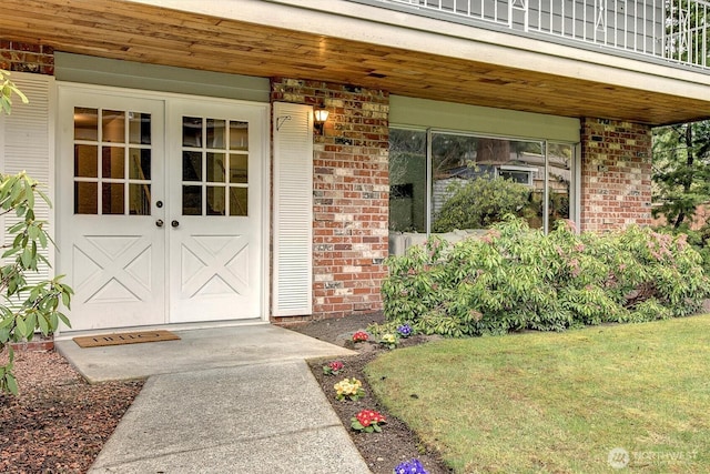 view of exterior entry with brick siding and a lawn