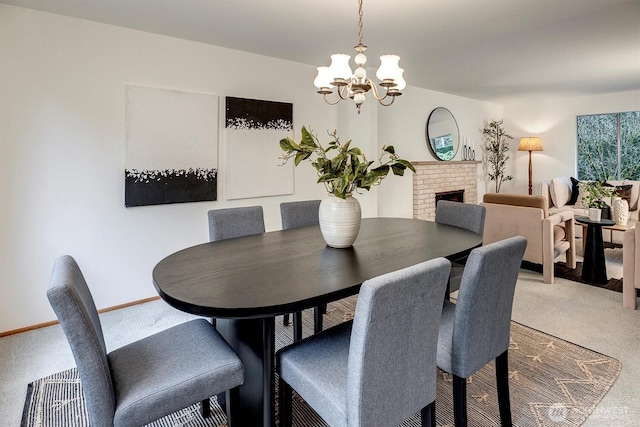 carpeted dining area featuring a chandelier, a brick fireplace, and baseboards