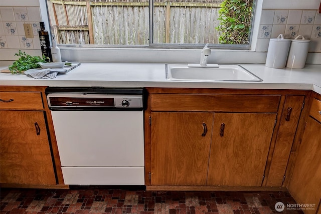 kitchen featuring dishwasher, light countertops, brown cabinets, and a sink