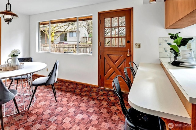 dining space featuring brick floor and baseboards