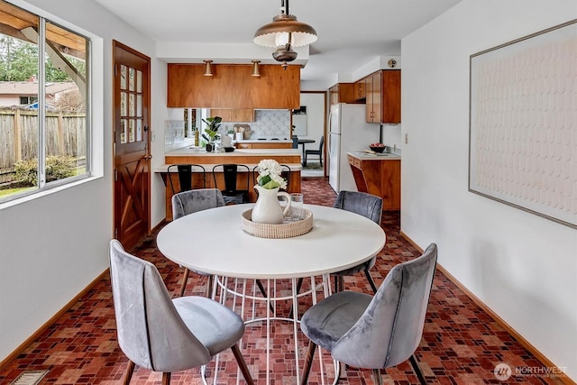 dining area featuring brick floor and baseboards