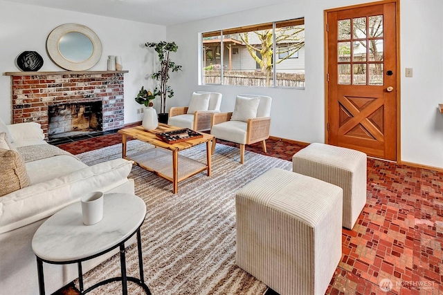 living room featuring a brick fireplace, baseboards, and brick floor