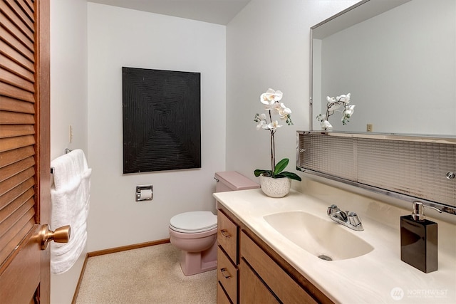 half bath with baseboards, toilet, and vanity