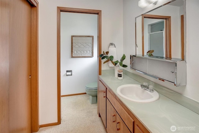 bathroom featuring vanity, toilet, baseboards, and a shower with shower door