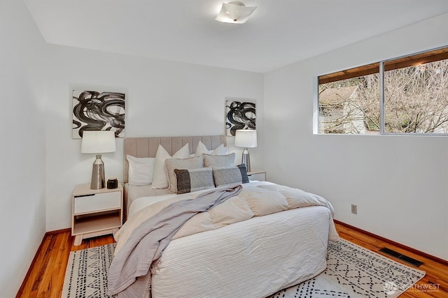 bedroom featuring visible vents, baseboards, and wood finished floors