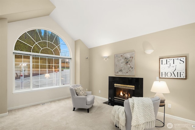 living area with a fireplace with flush hearth, lofted ceiling, carpet flooring, and baseboards