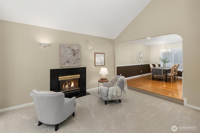 sitting room with arched walkways, carpet flooring, a fireplace with flush hearth, and baseboards