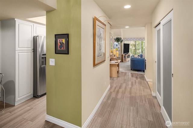 corridor featuring recessed lighting, wood tiled floor, and baseboards