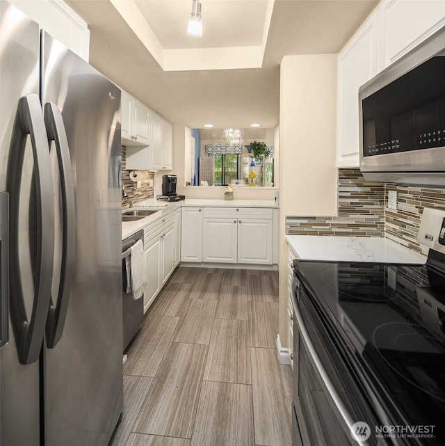 kitchen featuring light countertops, appliances with stainless steel finishes, a tray ceiling, and white cabinets