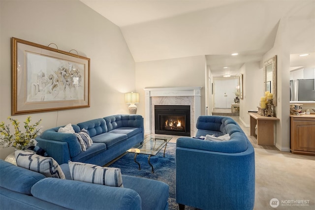 living area featuring light carpet, a premium fireplace, baseboards, and vaulted ceiling