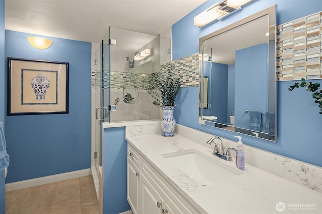 bathroom with baseboards, a stall shower, vanity, and tile patterned floors