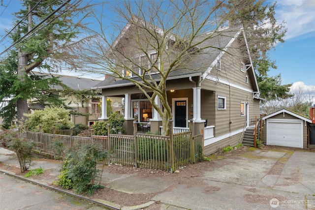 view of front of property featuring a fenced front yard, an outbuilding, aphalt driveway, a detached garage, and a porch