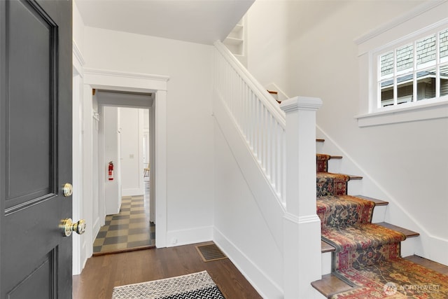 stairway with wood finished floors and visible vents