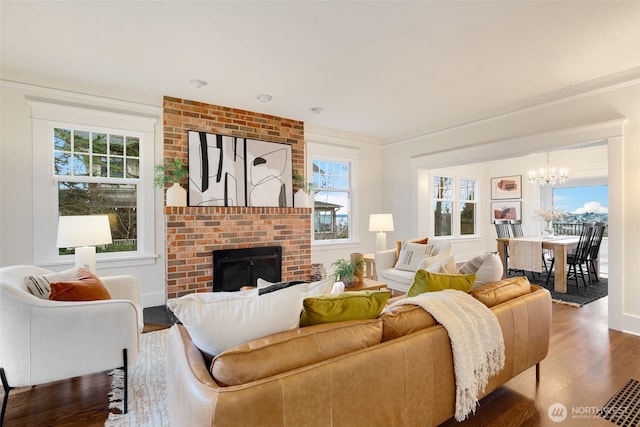 living area with crown molding, a fireplace, a notable chandelier, dark wood-type flooring, and baseboards