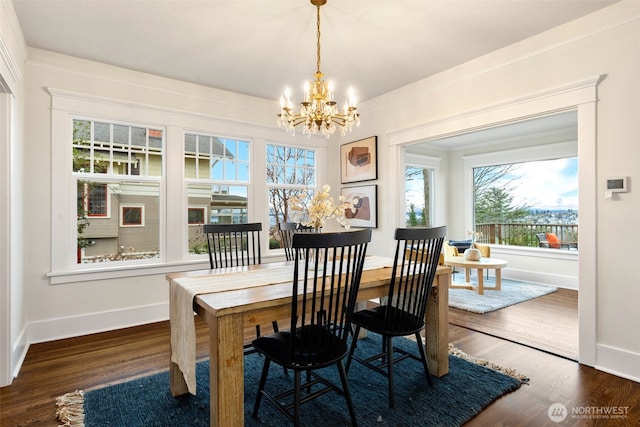 dining room featuring a chandelier, dark wood-style flooring, ornamental molding, and baseboards