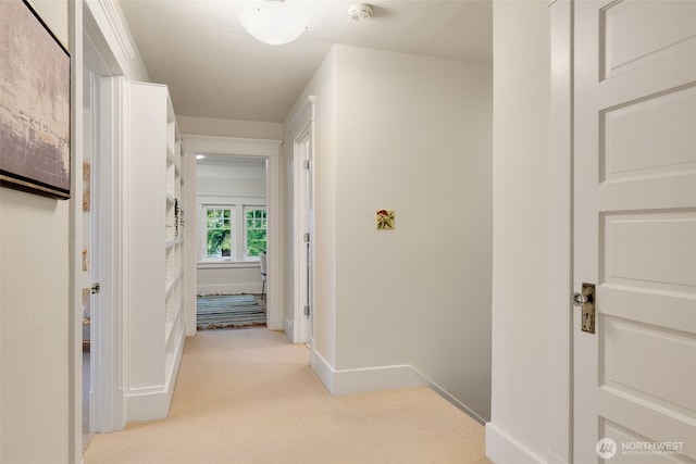 hall featuring light colored carpet and baseboards