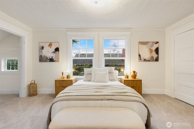 bedroom featuring a textured ceiling, crown molding, baseboards, and light colored carpet