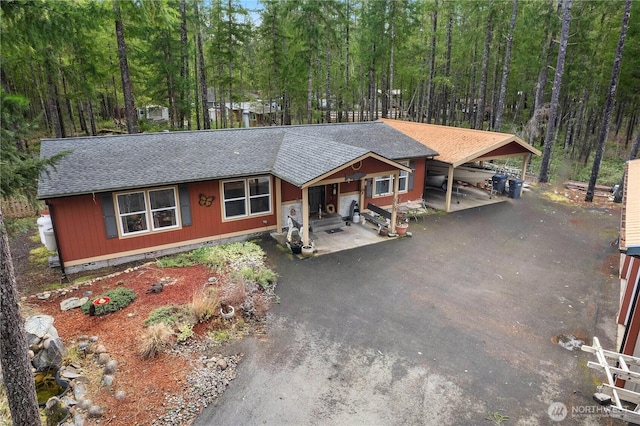 view of front of property with crawl space, a carport, driveway, and a shingled roof