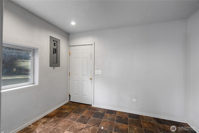 unfurnished room featuring stone finish floor, recessed lighting, electric panel, and baseboards