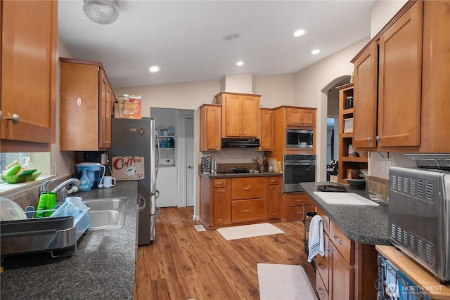 kitchen with stainless steel appliances, brown cabinetry, light wood-type flooring, and under cabinet range hood