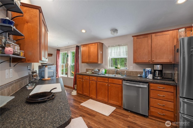 kitchen with open shelves, appliances with stainless steel finishes, dark countertops, and a sink