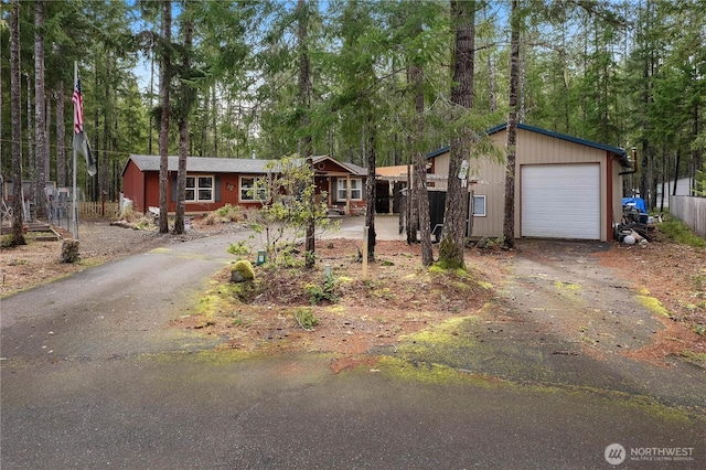 view of front of home with aphalt driveway, an attached garage, and fence