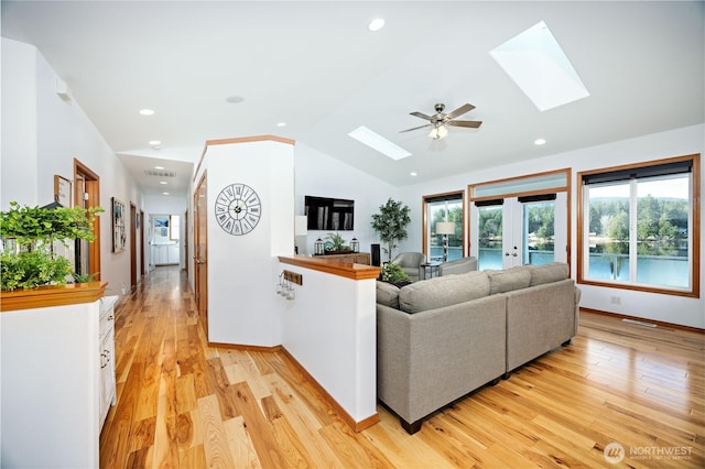 living area with light wood-style floors, vaulted ceiling with skylight, and recessed lighting