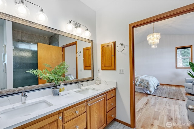 bathroom featuring wood finished floors, a notable chandelier, a sink, and double vanity