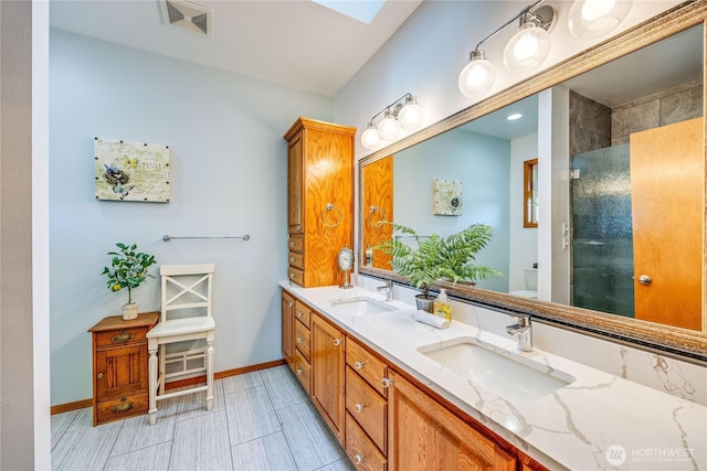 full bathroom featuring a skylight, tiled shower, a sink, and toilet