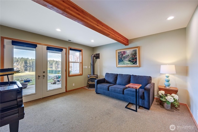 living room with a wood stove, carpet flooring, french doors, and beam ceiling