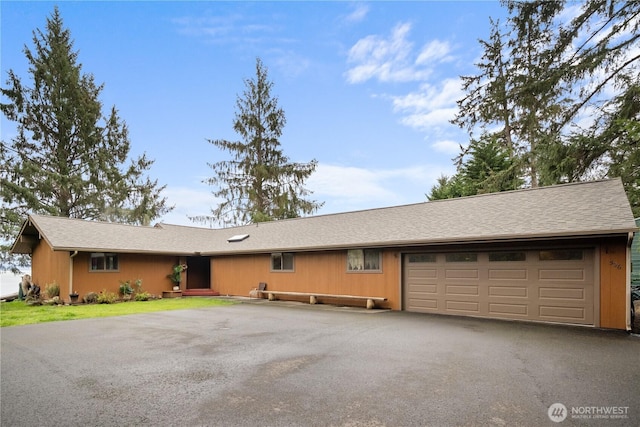 single story home featuring an attached garage and aphalt driveway