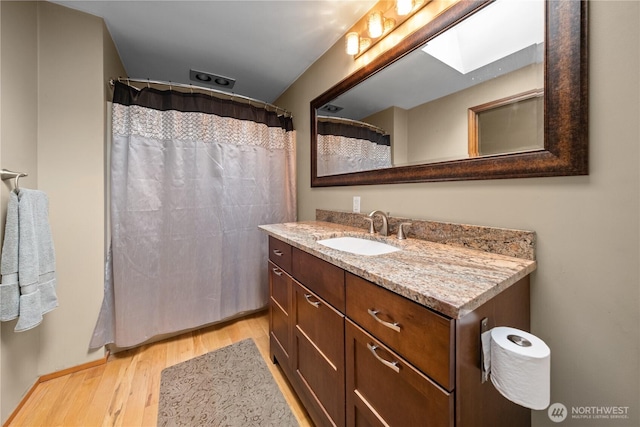 bathroom with a skylight, wood finished floors, and vanity