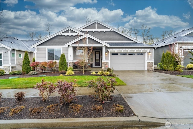 craftsman-style house featuring an attached garage, driveway, and stone siding