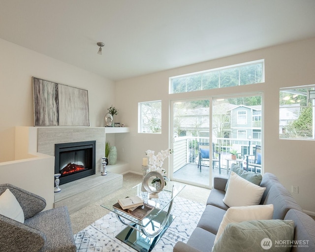 living room with light carpet, baseboards, and a glass covered fireplace