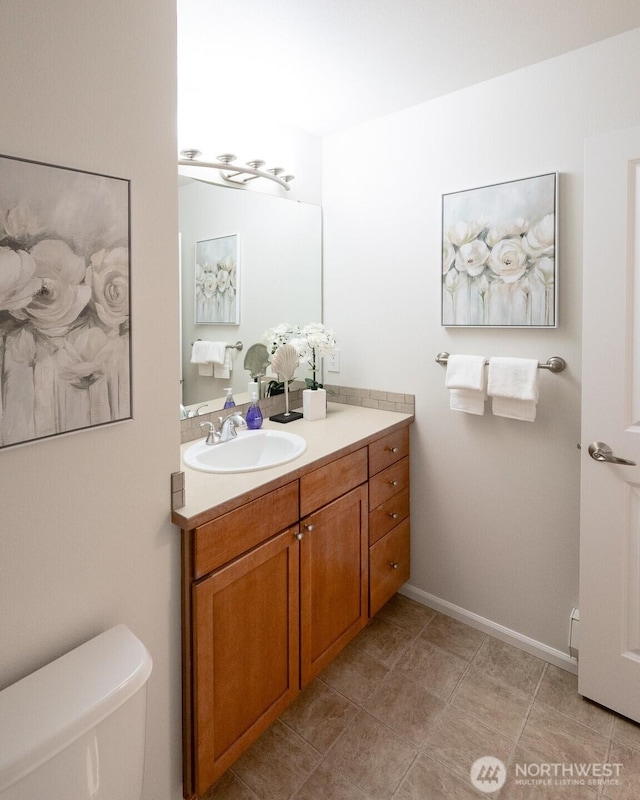 bathroom featuring toilet, vanity, and baseboards