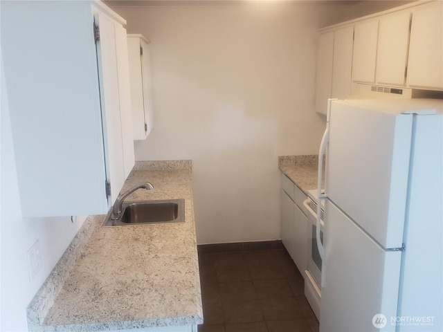 kitchen featuring freestanding refrigerator, light countertops, a sink, and dark tile patterned flooring