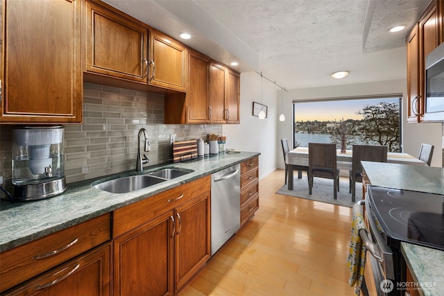 kitchen featuring brown cabinets, light wood finished floors, stainless steel appliances, and a sink