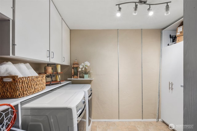 laundry room with washer and clothes dryer, rail lighting, cabinet space, and baseboards