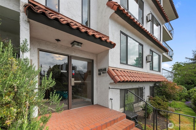 doorway to property with a tile roof and stucco siding