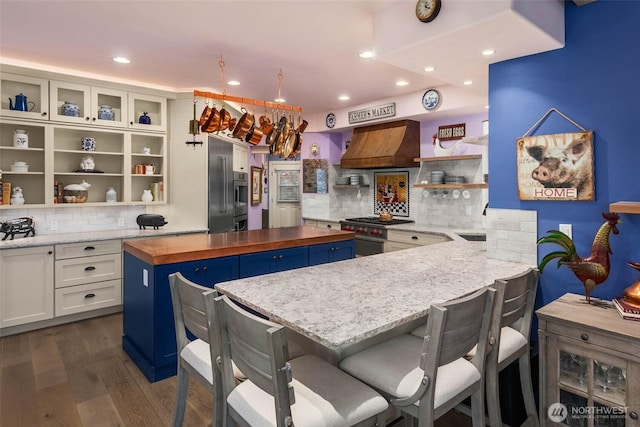 kitchen featuring gas cooktop, premium range hood, white cabinets, wooden counters, and open shelves