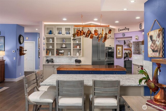 kitchen with dark wood-style flooring, stainless steel double oven, recessed lighting, and decorative backsplash