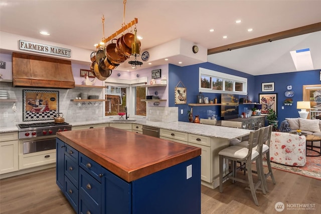 kitchen featuring vaulted ceiling with skylight, open floor plan, a sink, and open shelves