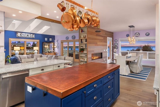 kitchen featuring blue cabinets, butcher block countertops, open floor plan, and stainless steel dishwasher