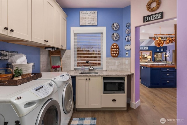 washroom with wood finished floors, a sink, cabinet space, and washer and dryer