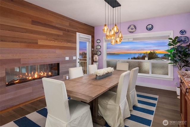 dining room with wood walls, a chandelier, wood finished floors, and a multi sided fireplace