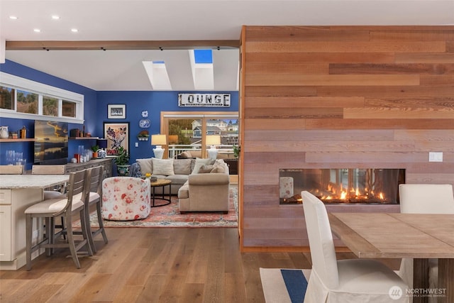 interior space with lofted ceiling, a multi sided fireplace, and wood finished floors