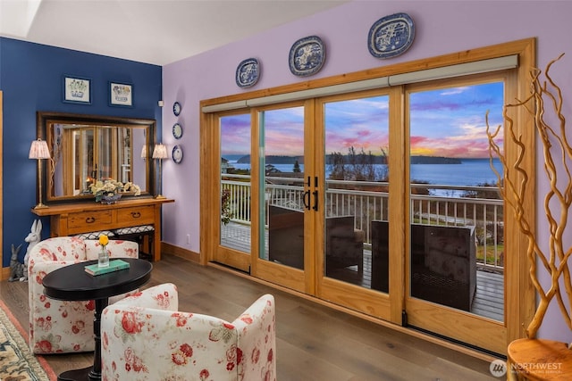 doorway featuring a water view, wood finished floors, and baseboards