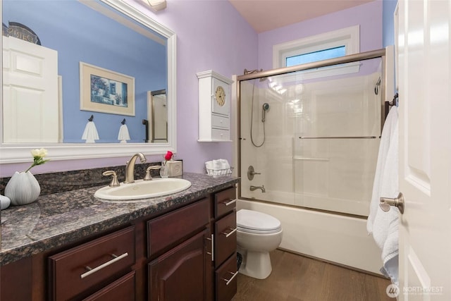 full bath with toilet, shower / bath combination with glass door, wood finished floors, and vanity