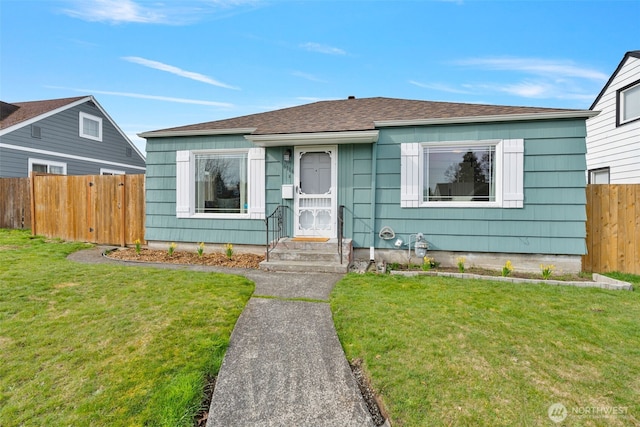 bungalow-style house with roof with shingles, a front yard, and fence