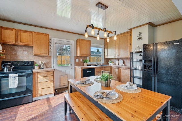 kitchen with black appliances, crown molding, light countertops, and a sink